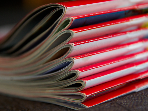 Ein Zeitschriftenstapel mit roten Zeitschriften, die übereinander liegen.